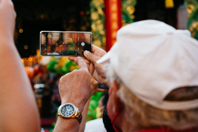 A person captures a vibrant street event with a smartphone, focusing on details and colors.